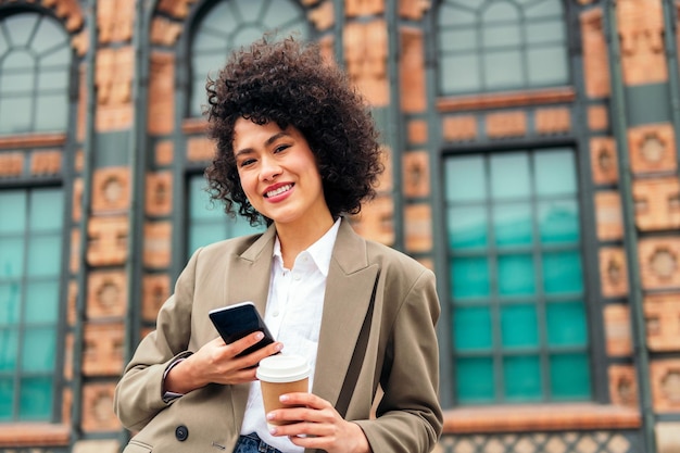 Mulher sorri feliz com um celular na mão