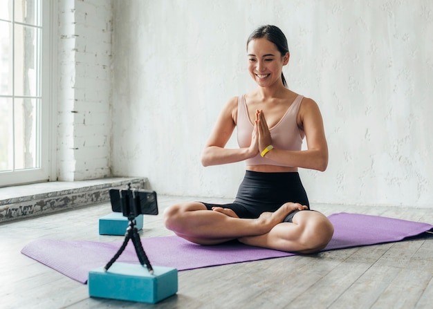 Mulher sorridente a meditar no tapete de fitness