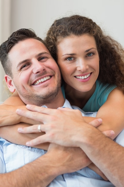 Mulher sorridente abraçando o homem em casa