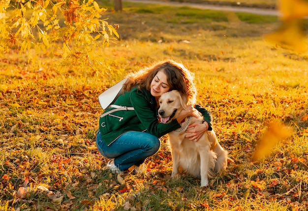 Mulher sorridente abraçando seu cachorro Golden Retriever perto do rosto