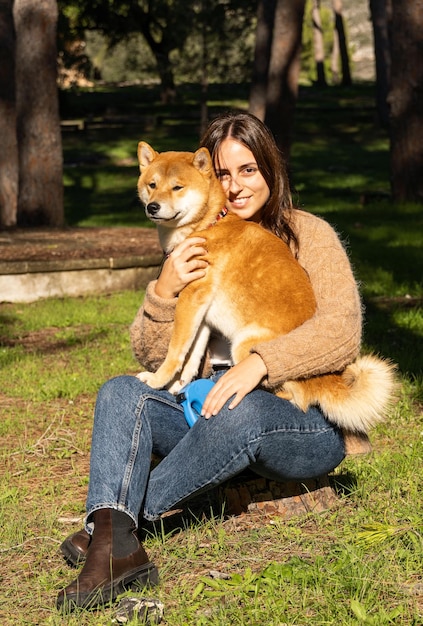 Mulher sorridente, abraçando um cachorro shiba inu