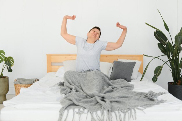 Mulher sorridente acordando e esticando na cama de manhã