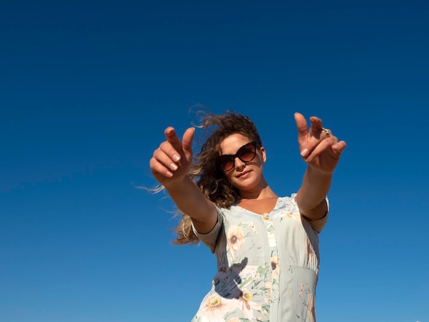 Mulher sorridente, alcançando as mãos na câmera à luz do sol