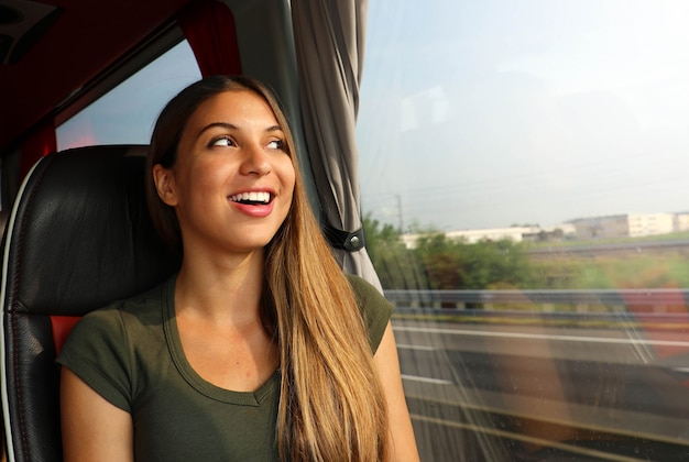 Mulher sorridente alegre feliz desfrutando de sua viagem de ônibus. Olhando pela janela.