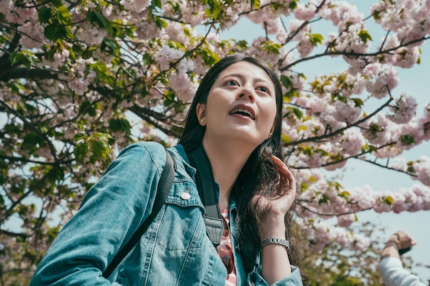 Mulher sorridente aprecia a vista de sakura