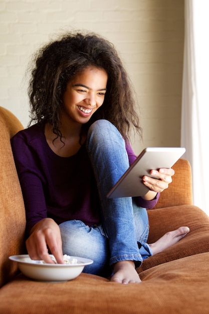 Mulher sorridente assistindo filme no tablet digital em casa