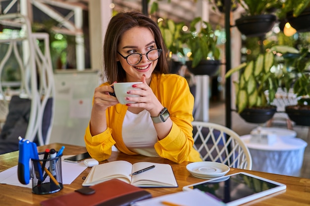 Mulher sorridente bebendo café em seu escritório.