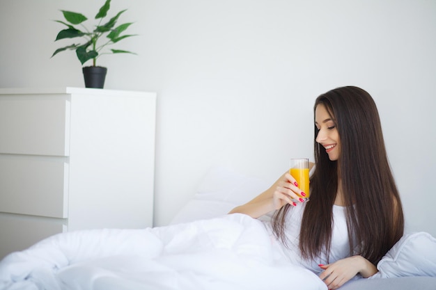 Mulher sorridente casual segurando um copo de suco de laranja