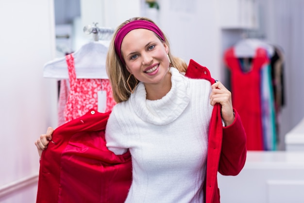 Mulher sorridente colocando casaco vermelho