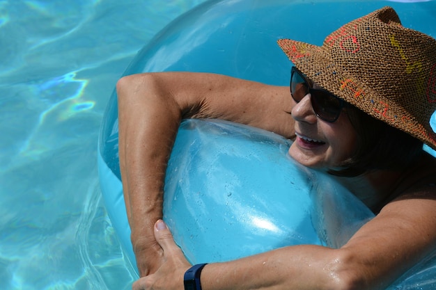 Foto mulher sorridente com anel inflável nadando na piscina