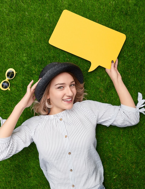 Mulher sorridente com balão de fala na grama verde