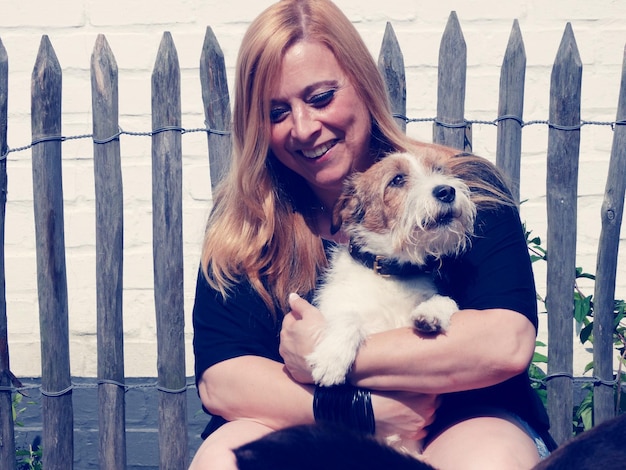 Mulher sorridente com cão contra a cerca