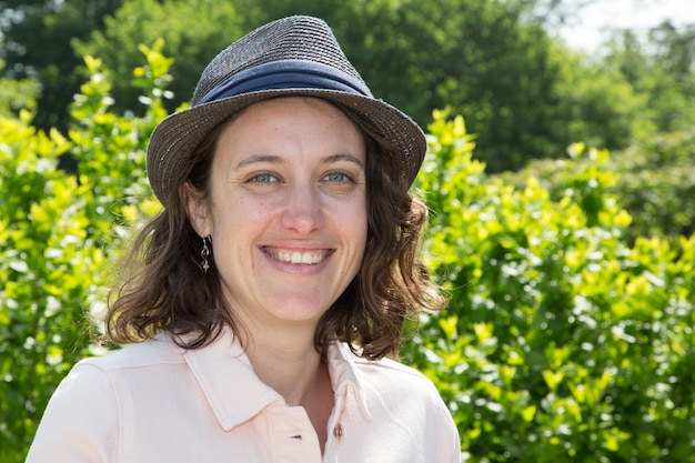 Mulher sorridente com chapéu azul em dia de verão ao ar livre