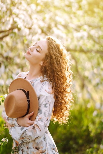 Mulher sorridente com chapéu no parque primavera O conceito de relaxar a liberdade de viagem