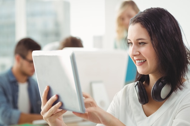 Mulher sorridente com fones de ouvido usando tablet digital