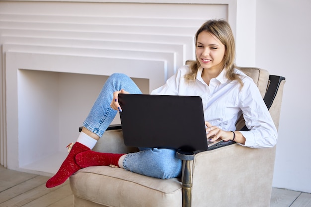 Mulher sorridente com laptop faz teletrabalho na sala