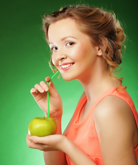 Mulher sorridente com maçã e palhas cocktail