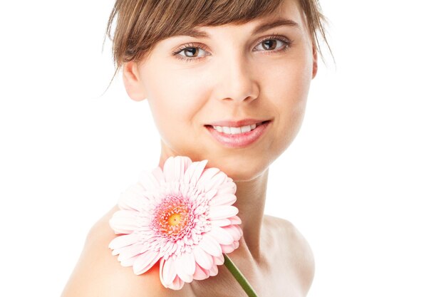 Mulher sorridente com maquiagem criativa e flor gerbera na cor de fundo