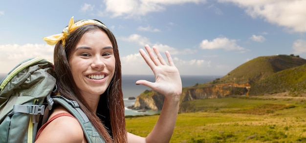 Foto mulher sorridente com mochila na costa de big sur