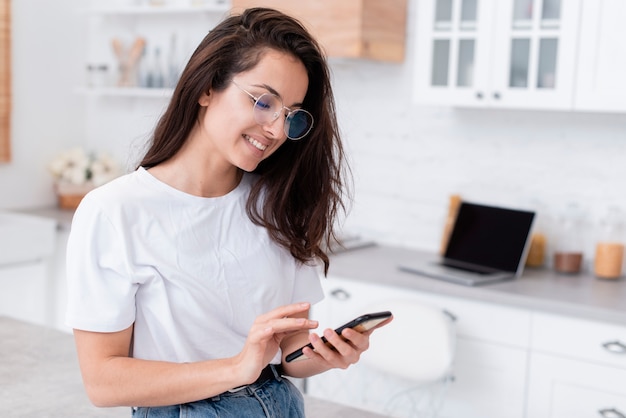 Foto mulher sorridente com óculos, olhando para o telefone