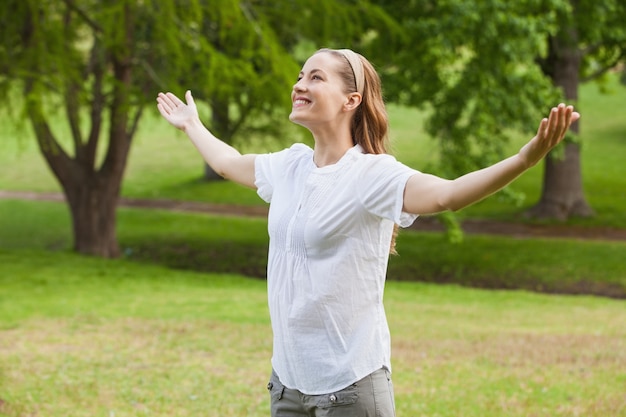 Mulher sorridente com os braços estendidos no parque