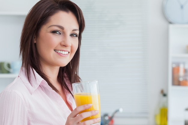 Mulher sorridente com suco de laranja