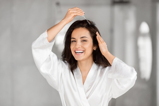 Mulher sorridente com uma túnica branca brincando com o cabelo