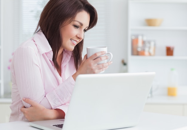 Mulher sorridente com xícara de café com laptop