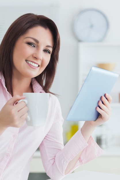 Mulher sorridente com xícara de café e tableta digital