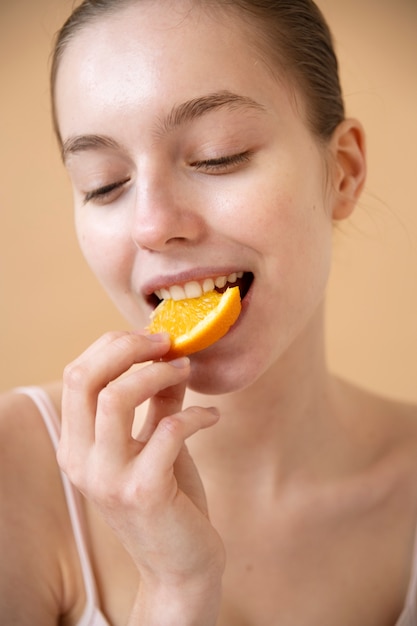 Mulher sorridente comendo laranja alto ângulo