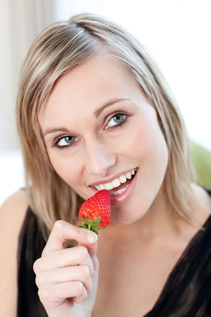 Foto mulher sorridente comendo um morango