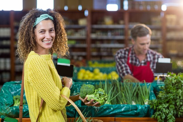 Mulher sorridente comprando legumes na seção orgânica