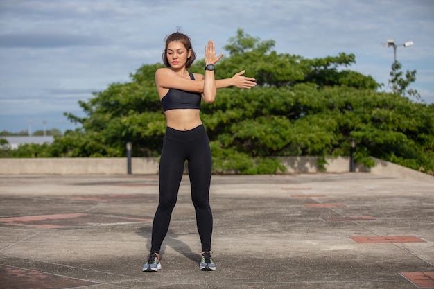 Mulher sorridente corredor asiático fazendo exercícios de alongamento, preparando-se para o treino matinal e o conceito de estilo de vida na cidade