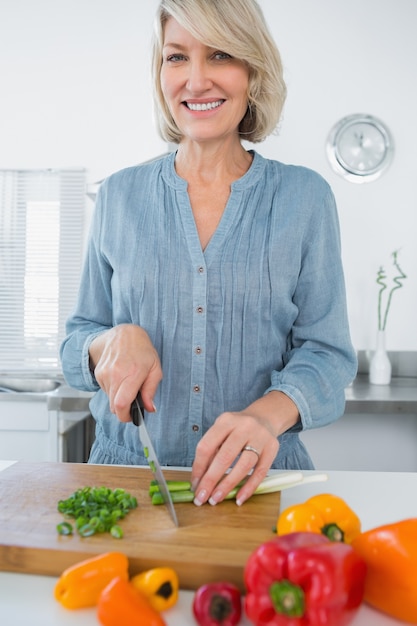 Mulher sorridente cortando vegetais