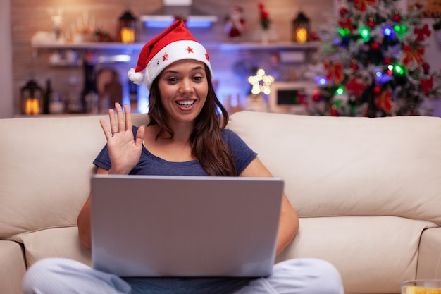 Foto mulher sorridente cumprimentando amigos remotos curtindo o natal juntos