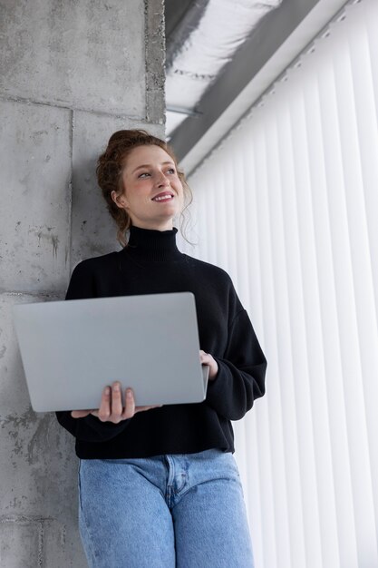 Foto mulher sorridente de baixo ângulo segurando laptop