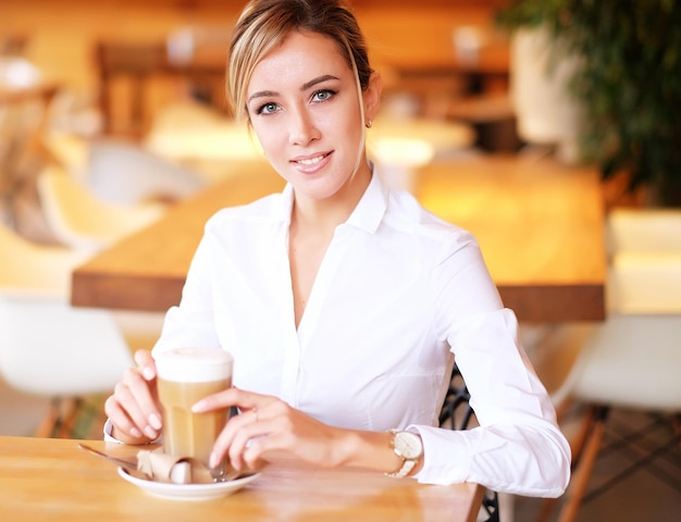Mulher sorridente de bom humor com uma xícara de café sentado no café