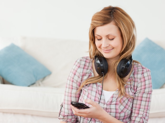 Mulher sorridente de cabelos loiros com fones de ouvido e leitor de mp3