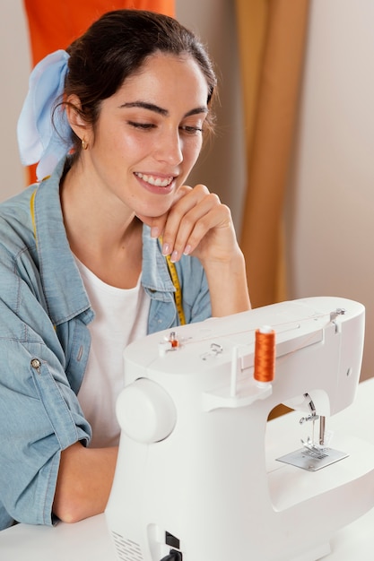 Mulher sorridente de close-up observando máquina de costura