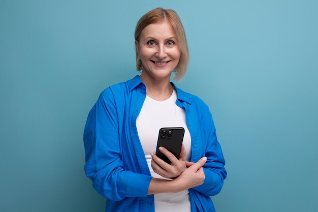 Mulher sorridente de meia idade dominando a técnica da modernidade e segurando um smartphone com um