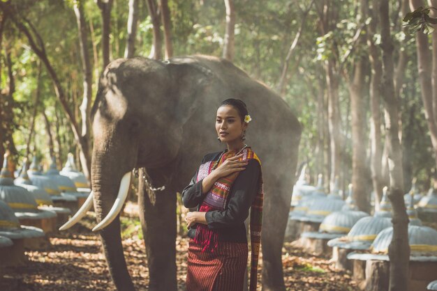 Mulher sorridente de pé com um elefante na floresta