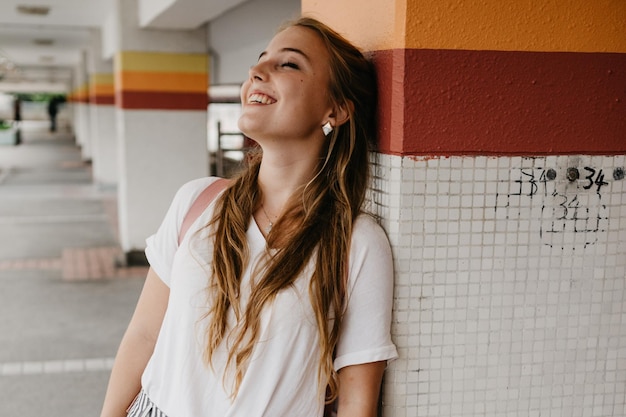 Mulher sorridente de pé contra a coluna