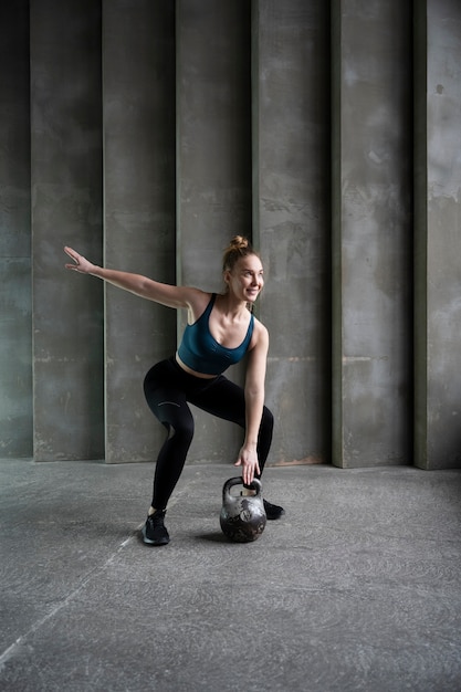 Mulher sorridente de tiro completo treinando com kettlebell