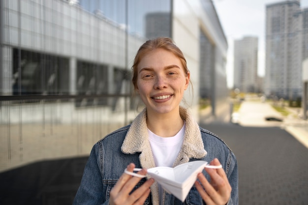 Foto mulher sorridente de vista frontal tirando a máscara