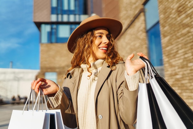 Mulher sorridente depois de fazer compras na rua da cidade Conceito de venda de compras Conceito de compras on-line