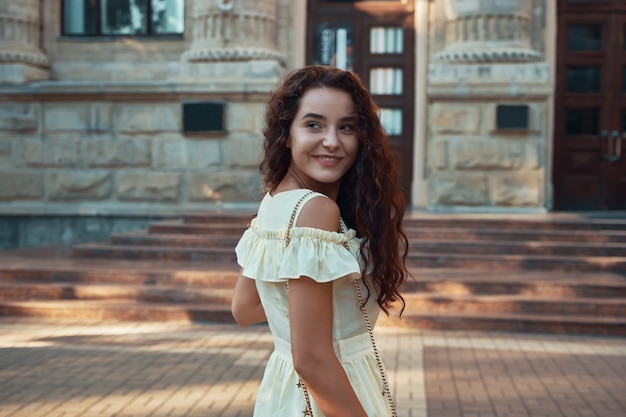 Mulher sorridente desviando o olhar por cima do ombro enquanto caminhava