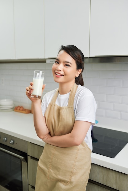 Mulher sorridente e atraente tomando café da manhã no interior da cozinha