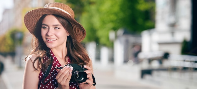 Mulher sorridente e atraente turista caminhando pela cidade de verão e tirando fotos de edifícios