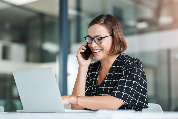 Mulher sorridente e chamada telefônica no escritório com laptop para trabalho como recepcionista apoio administrativo e habilidade de multitarefa Funcionária feminina on-line e conversação para confirmar nomeação e planejamento