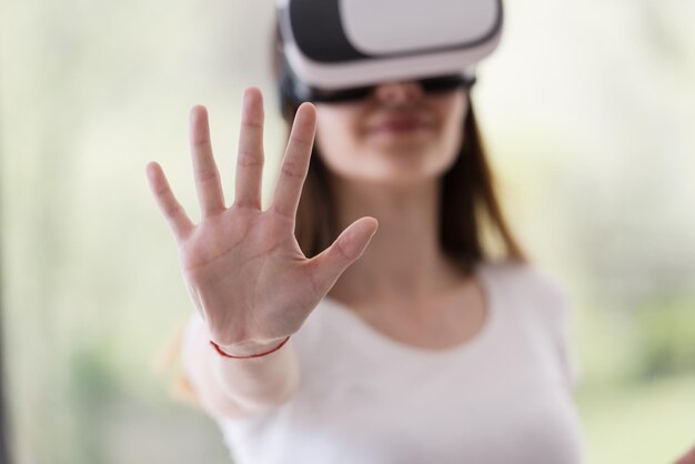 Mulher sorridente e feliz obtendo experiência usando óculos de realidade virtual com fone de ouvido VR em casa